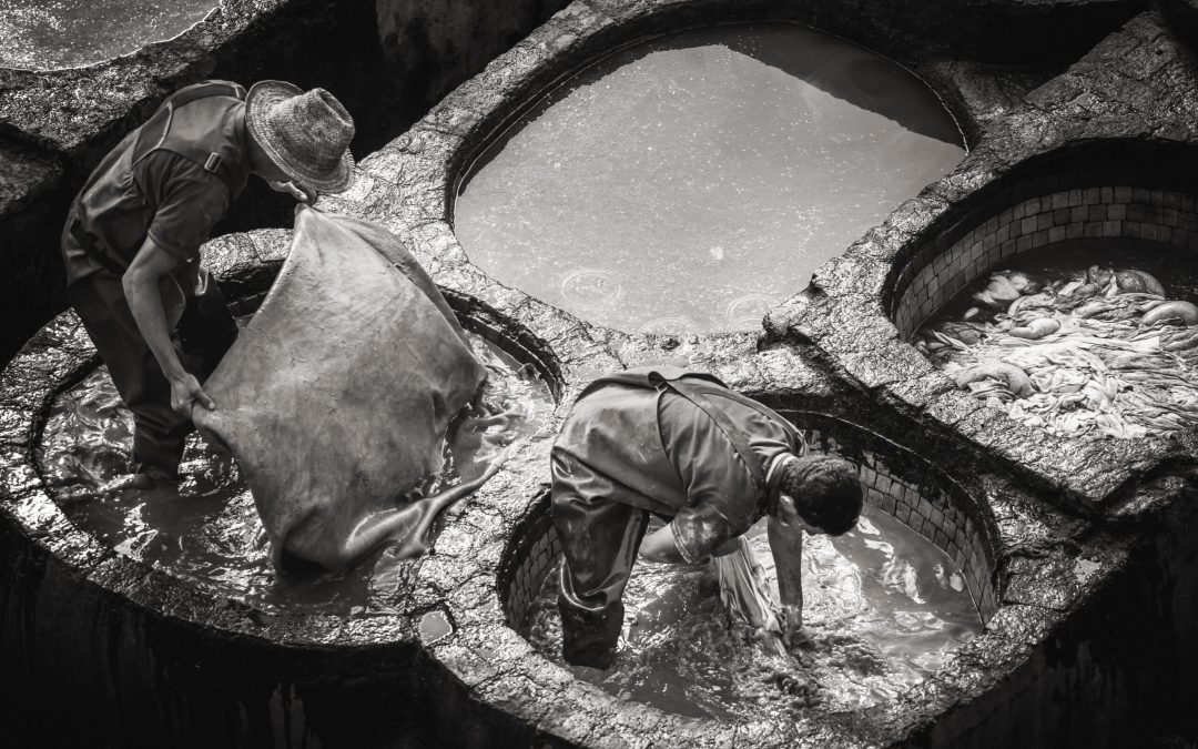 Men working at Chouwara Leather traditional tannery in ancient medina of Fes El Bali, Morocco, Africa.